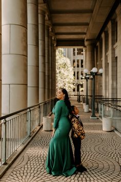 a woman in a long green dress standing next to another woman wearing a leopard print purse