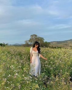 a woman is standing in a field with flowers