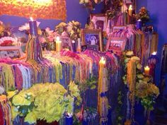 a room filled with lots of different types of flowers and pictures on the wall next to candles