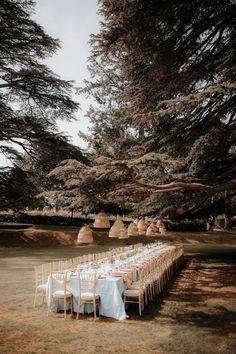 a long table is set up in the middle of a field for an outdoor wedding