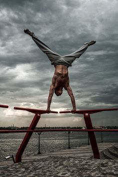 a man doing a handstand on top of a red rail