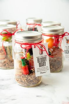 four mason jars filled with various types of food and labeled in red ribbon tied around them