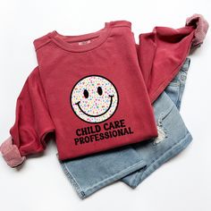 Celebrate your love of little kids as well as your career with this sweatshirt!   Now available in Comfort Colors, this Unisex Crew Neck sweatshirt is destined to be your favorite, most comfortable sweatshirt!   Featuring soft, beautiful colors, you will surely find the right one for you. Luxurious comfort and style are what this unisex, garment-dyed sweatshirt is all about. It's 80% ring-spun cotton and 20% polyester and the fabric is 3-end garment-dyed, ring-spun, color-blast fleece with a 100% cotton face.  Each sweatshirt comes with a relaxed fit, medium-heavy fabric, rolled-forward shoulder, and a back neck patch.  Care Instructions: Machine Wash Cold Non Chlorine Bleach if Needed Tumble Dry, Low Heat Do Not Iron, Do Not Dry Clean Please refer to the size chart for sizing information! Face Family, Family Child Care, Daycare Providers, Child Care, Smiley Face, Childcare, Comfort Colors, Smiley, Beautiful Colors