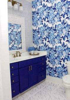 a blue and white bathroom with floral wallpaper