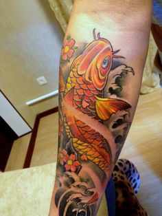 a person with a tattoo on their arm holding a cell phone and a fish in the water