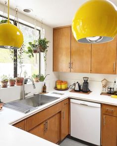 a kitchen with wooden cabinets and yellow lights hanging from the ceiling over the stove top