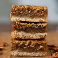 three pieces of pecan bar stacked on top of each other with nuts around them