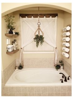 a bath tub sitting under a window next to a shelf filled with potted plants