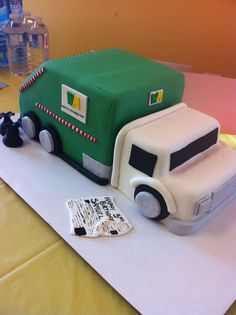 a green and white truck cake sitting on top of a table next to water bottles