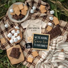 a table topped with marshmallows and chocolate on top of a plaid blanket