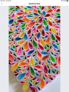 an art piece made out of paper with colorful drops on the bottom, and a white background