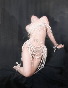 a woman with pearls on her body is posing for the camera and wearing an elaborate outfit