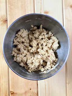 a metal bowl filled with food on top of a wooden table