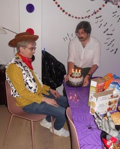 two men sitting at a table with a birthday cake