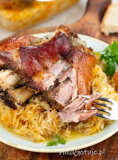 a white plate topped with meat and rice on top of a wooden table next to bread