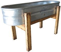 a large metal tub with wooden legs on an isolated white background for use as a planter