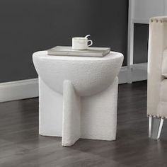 a chair and table in a room with wood flooring, gray walls and white furniture