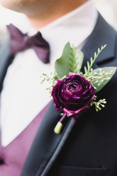 a man in a tuxedo wearing a boutonniere with purple flowers