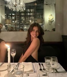 a woman sitting at a table with a candle in front of her and two other people