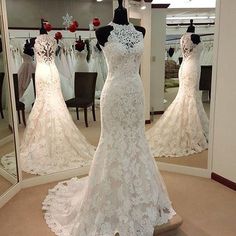 a white wedding dress on display in front of a mirror with other dresses behind it