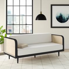 a white couch sitting next to a window on top of a tiled floor in front of a potted plant