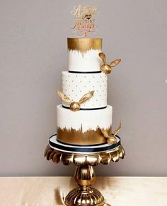 a white and gold wedding cake with two birds on the top, sitting on a table