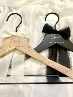 two personalized wooden hangers with black and white bows on them, sitting next to each other