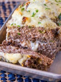 a loaf of meatloaf with cheese and herbs is on a metal tray, ready to be eaten