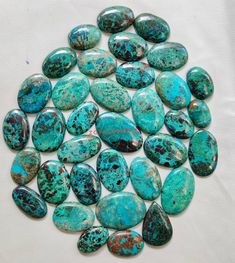 turquoise colored stones are arranged on a white surface, with brown and blue speckles