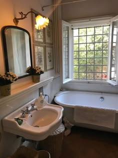 a bathroom with a tub, sink and window in the corner next to the bathtub