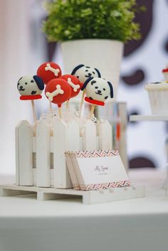 cake pops decorated with dog heads and bones are on display in front of a potted plant