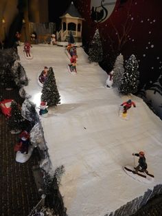 a group of people riding skis on top of a snow covered slope next to trees