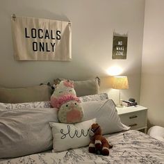 two stuffed animals are on the bed in this small room with white walls and gray linens