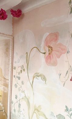 a bathroom with pink flowers painted on the wall and a mirror in front of it