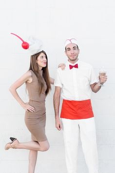 a man and woman dressed in costumes posing for the camera with one holding a drink