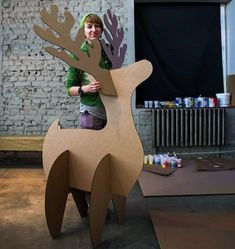 a woman standing next to a cardboard reindeer