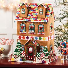 a gingerbread house with candy and candies on a table next to a christmas tree