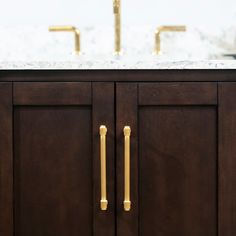 a bathroom vanity with two sinks and gold handles