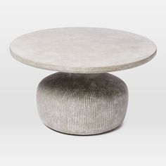 a white table sitting on top of a wooden table next to a gray and white vase