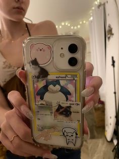 a person holding up a cell phone with stickers on it in front of a mirror