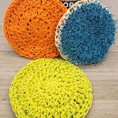 three crocheted round coasters sitting on top of a wooden table