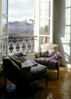 a dog sitting on top of a window sill next to a chair and ottoman