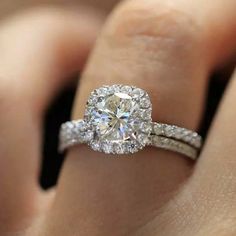 a woman's hand with a diamond ring on top of her finger and the engagement band