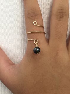 a person's hand with two rings on it and a ring that has a black bead in the middle