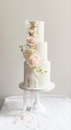 a three tiered white cake with pink flowers on top