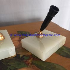 a pen sitting on top of a white block next to a candle holder with a black handle