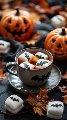 pumpkins and marshmallows in a teacup on a black tablecloth