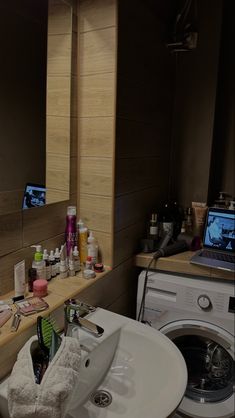 a washer and dryer in a bathroom with the sink full of personal care items