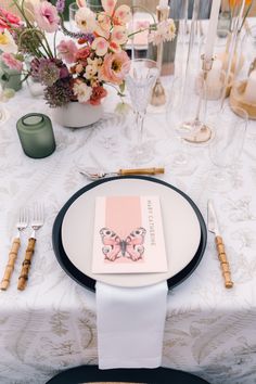 the table is set with an elegant butterfly place card and utensils for guests