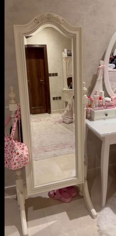 a white dressing table with a mirror on top of it next to a pink chair